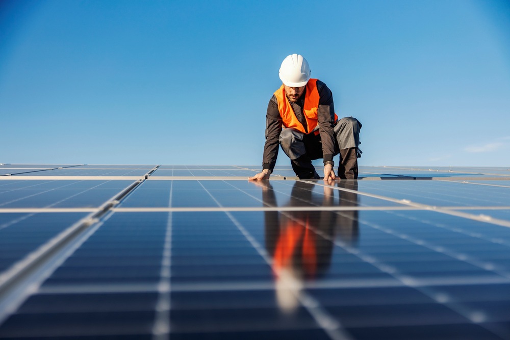 Homem sentado mexendo em placa de energia solar