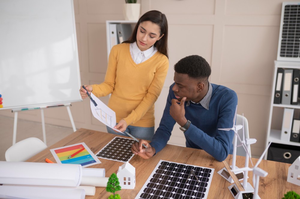 Duas pessoas conversando em um escritório e uma delas provavelmente está apresentando uma proposta comercial de energia solar